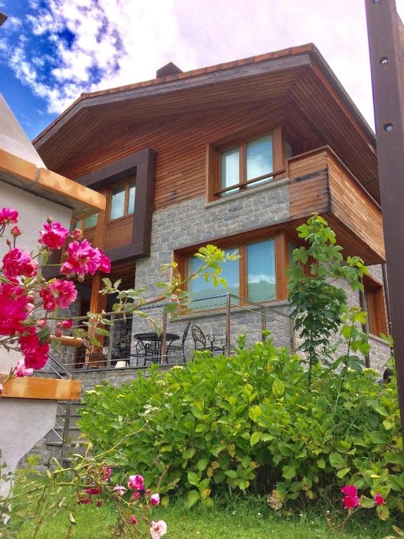 Fachada de Casa Maru — apartamento de piedra y madera con terraza y jardín florido